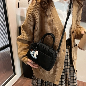 Black bowling handbag with a cute rocking horse charm shown in a cozy lifestyle setting