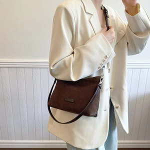 Vintage dunkelbraune Wildleder-Tragetasche mit Lederriemen an einem Modell im Minimal-Stil