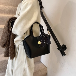 Sac seau minimaliste en cuir noir avec foulard à pois et finitions métalliques dorées