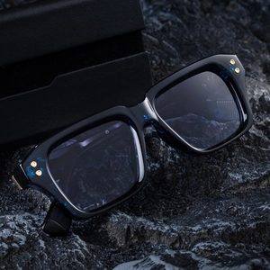 Men's square polarized sunglasses in blue frame with gold rivets on a dark rock surface
