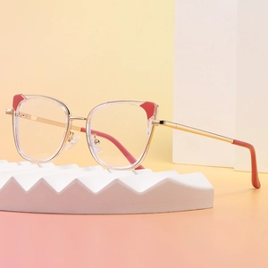 Cat eye glasses with clear frames and red accents on a white textured stand