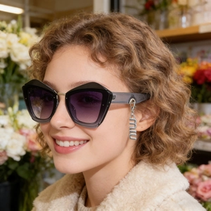 Détail de lunettes œil-de-chat avec verres dégradés violets et breloque en métal argenté