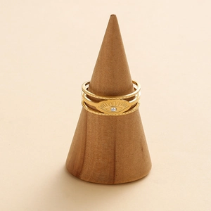 Detailed view of 14K gold plated evil eye rings on a wooden display stand