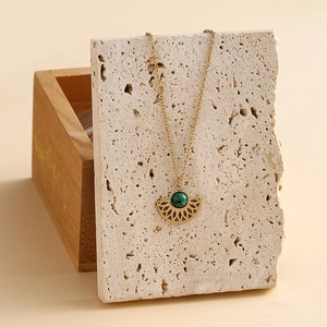 Bohemian gold stainless steel fan-shaped necklace with turquoise stone on travertine