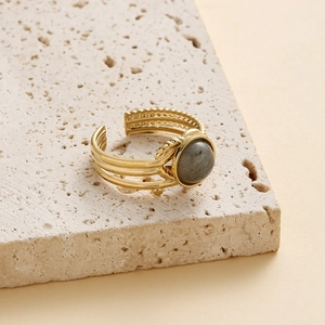 Gold stainless steel wide ring featuring a grey gemstone on a natural stone tray