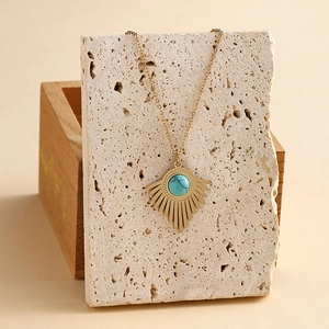 14K Goldkette mit Türkis-Anhänger im Sonnenstrahl-Design auf beigefarbenem Stein
