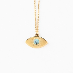 Golden evil eye necklace with turquoise stone inlay and sunburst engraving on white background