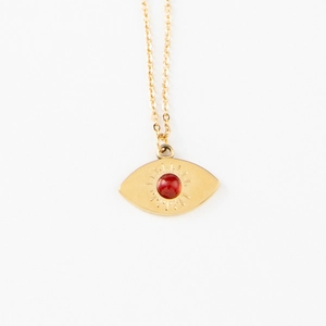 Gold eye pendant necklace with red natural stone and engraved sunburst on white background