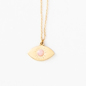Detail of gold evil eye pendant with pink stone and sunburst engraving on a fine chain
