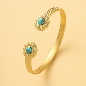 Detail of vintage gold open bangle featuring hammered texture and dual turquoise stones