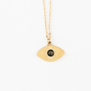 Close-up of golden stainless steel necklace featuring evil eye pendant with black stone