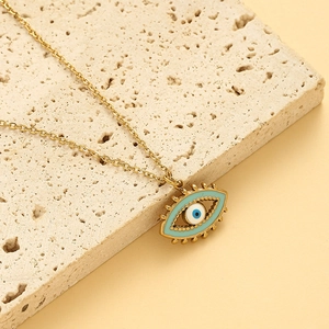 Détail du collier œil protecteur doré avec émail bleu sur un fond en pierre texturée