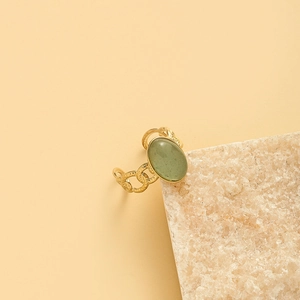 Macro detail of retro gold-plated ring with twisted chain texture and oval green stone