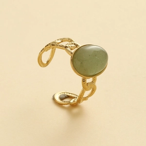 Detail of vintage gold ring with oval green gemstone and hammered open band