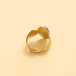Macro detail of gold adjustable ring featuring oval grey stone and vintage engraved texture
