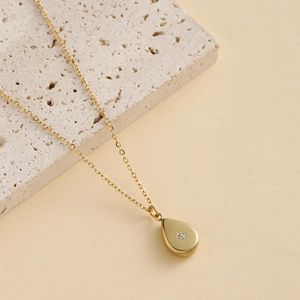 Détail macro du pendentif goutte dorée avec zircon et gravure d'étoile brillante