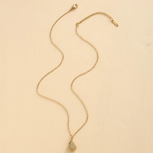 Détail macro du pendentif goutte dorée avec diamant rond sur chaîne ajustable