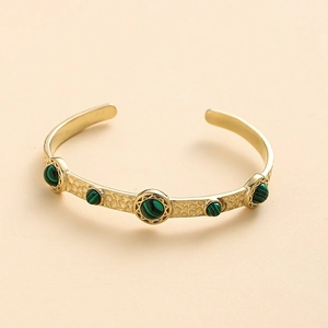 Détail d'un bracelet manchette doré bohème avec pierres turquoise et texture alvéolée