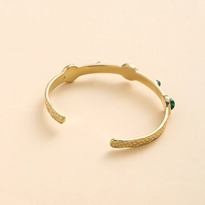Vue détaillée du bracelet jonc martelé plaqué or avec incrustations de pierres vertes