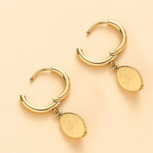 Détail de boucles d'oreilles dorées avec créoles en C et pendentifs texturés