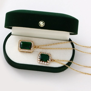 Détail de colliers avec pendentif émeraude et diamants dans un écrin en velours