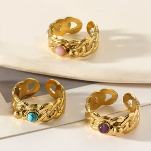 Vintage gold twist rings with colorful natural stones on white marble surface