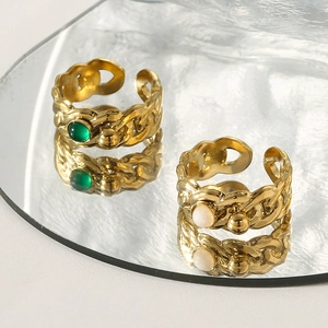 Vintage gold twist rings set with green and white gemstones on reflective surface