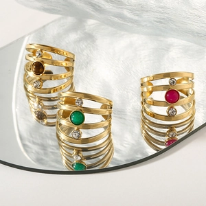 Detailed view of three layered gold-plated rings with natural gemstones on a mirror surface