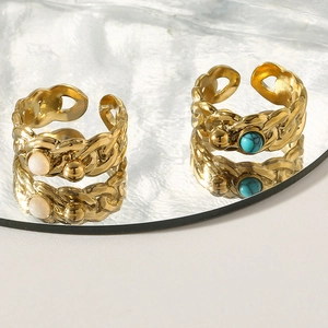 Detail of vintage gold rings featuring turquoise and opal stones with chain texture