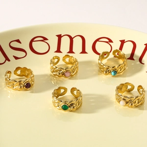 Detailed top view of five gold braided rings with colorful natural stones on a tray