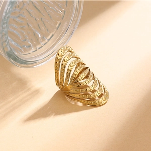 Gros plan d'une bague dorée multi-rangs avec texture pointillée et design incurvé
