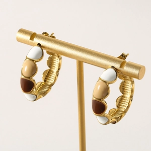 Detail of C-shaped hoop earrings featuring colorful enamel segments on gold plating