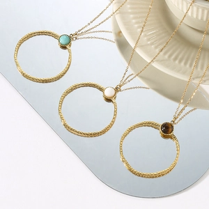 Macro detail of gold hammered round pendants with turquoise and natural stone inlay