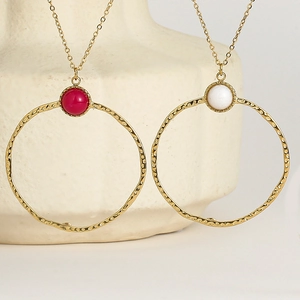 Detailed view of hammered gold circle pendants with red and white marble beads