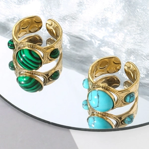 Vintage gold-plated rings with malachite and turquoise stones on a circular mirror surface