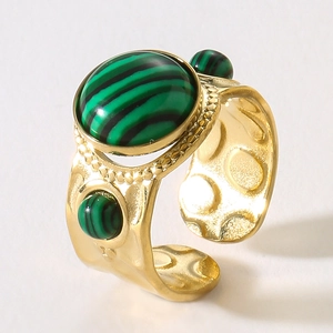 Macro detail of hammered gold ring featuring three malachite green gemstones in retro style