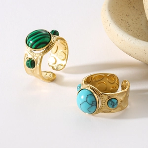 Detailed macro view of two gold rings with green and turquoise stones in vintage style