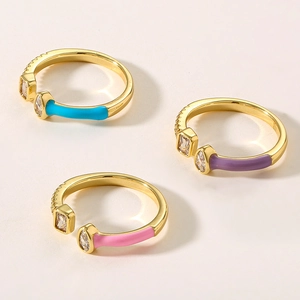 Close-up of three gold-plated copper rings with colorful enamel and zircon crystals