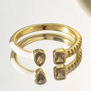Macro detail of gold open ring featuring white enamel, teardrop and rectangle zircons
