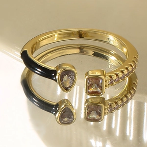 Detail of gold-plated open ring featuring pink crystals and black enamel drip design