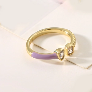 Macro detail of gold-plated copper ring with purple enamel and zircon inlay accents