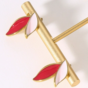 Detailed close-up of leaf earrings with red and white enamel on a gold-tone metal base