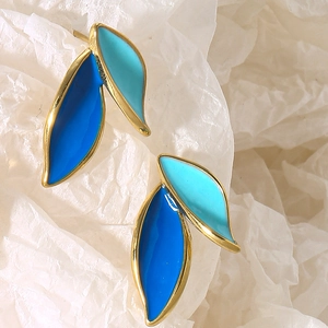 Macro view of blue enamel leaf earrings with gold trim and intricate textures