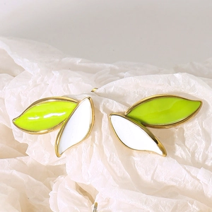 Detail of leaf stud earrings with green and white enamel and gold finish on textured paper