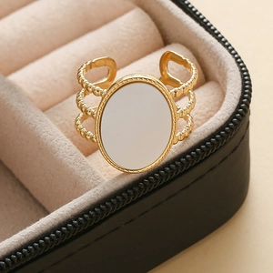 Détail d'une bague ajustable plaquée or 18K avec insert blanc ovale et texture perlée