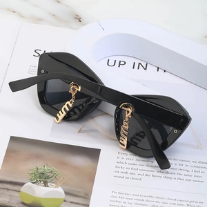 Lunettes de soleil œil de chat noires chic avec pendentifs en métal doré à la mode