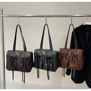 Detail of vintage pleated shoulder bags with bow accents in brown and black faux leather