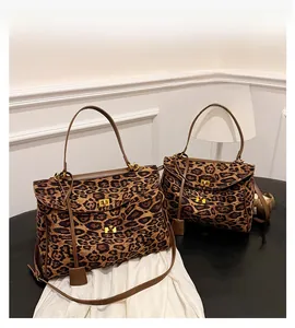 Detail view of leopard print tote bag with gold twist lock and adjustable brown leather straps