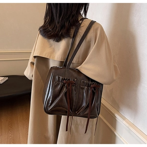 Detail of vintage brown shoulder bag with pleated texture and bow on beige trench coat