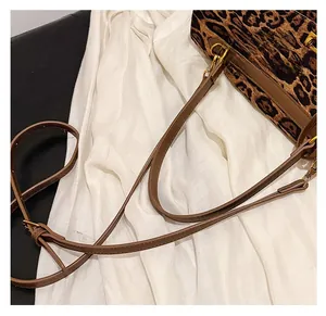 Detail of adjustable brown leather strap and gold buckle on leopard print tote bag